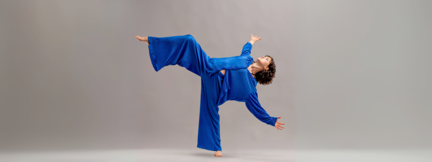 Dancer dressed in blue, leaning all the way back and balanced on one leg, with outstretched arms.