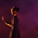 Dancer in purple with purple background looking at their hand.